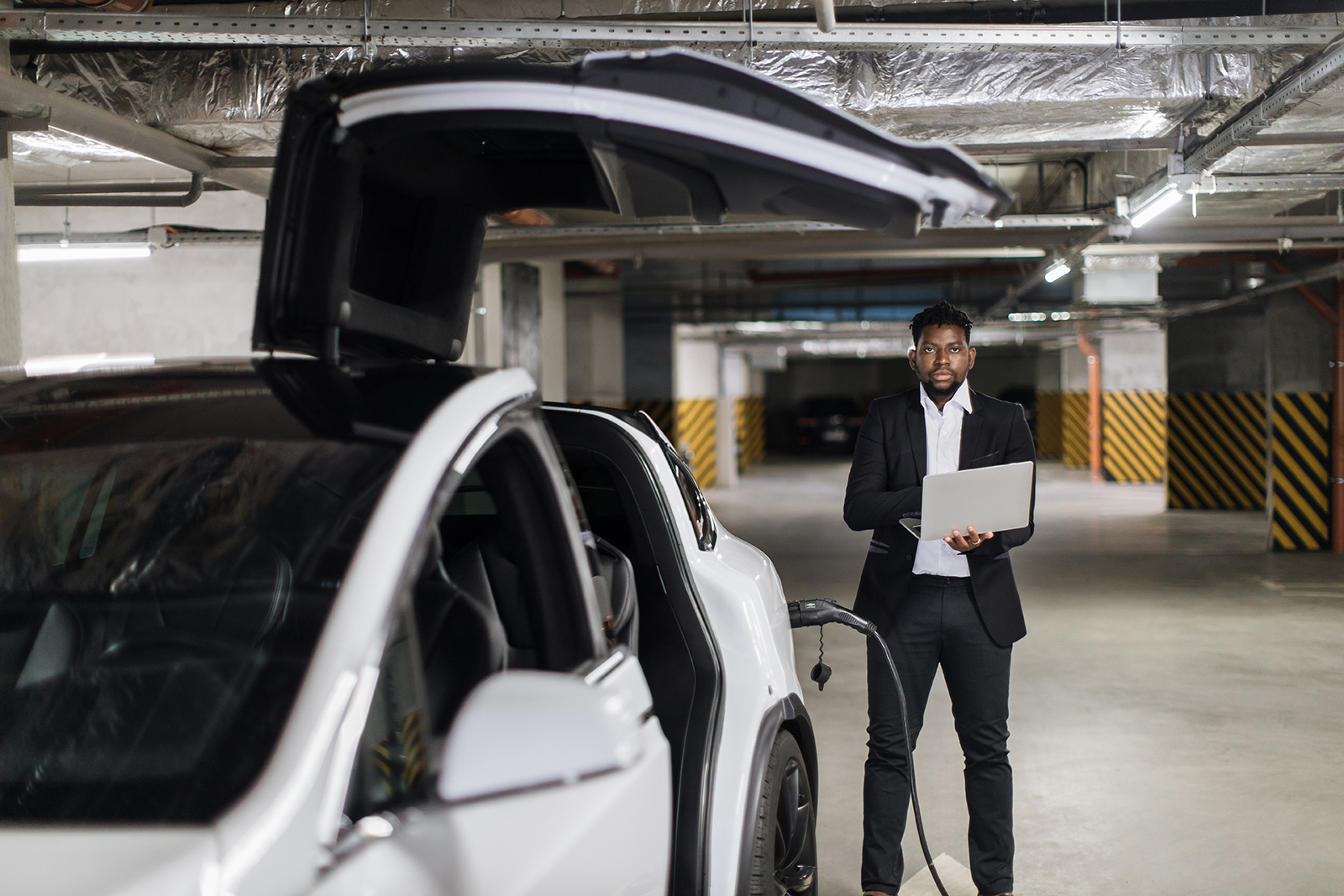 Employee with laptop working in EV underground garage